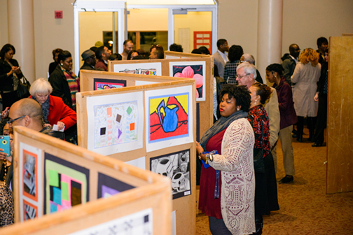 Attendees at the 2015 Realizing the Dream Concert examine artwork created by area students in the Moody Music Building Concert Hall lobby.