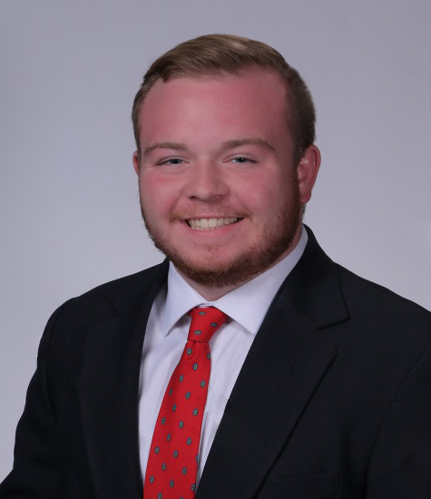 Headshot of Matthew “Drake” Southern wearing a black suit with red tie