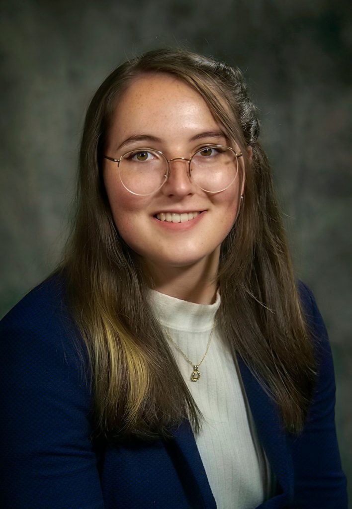 Headshot of Abbie Giunta wearing a dark blazer and white turtleneck