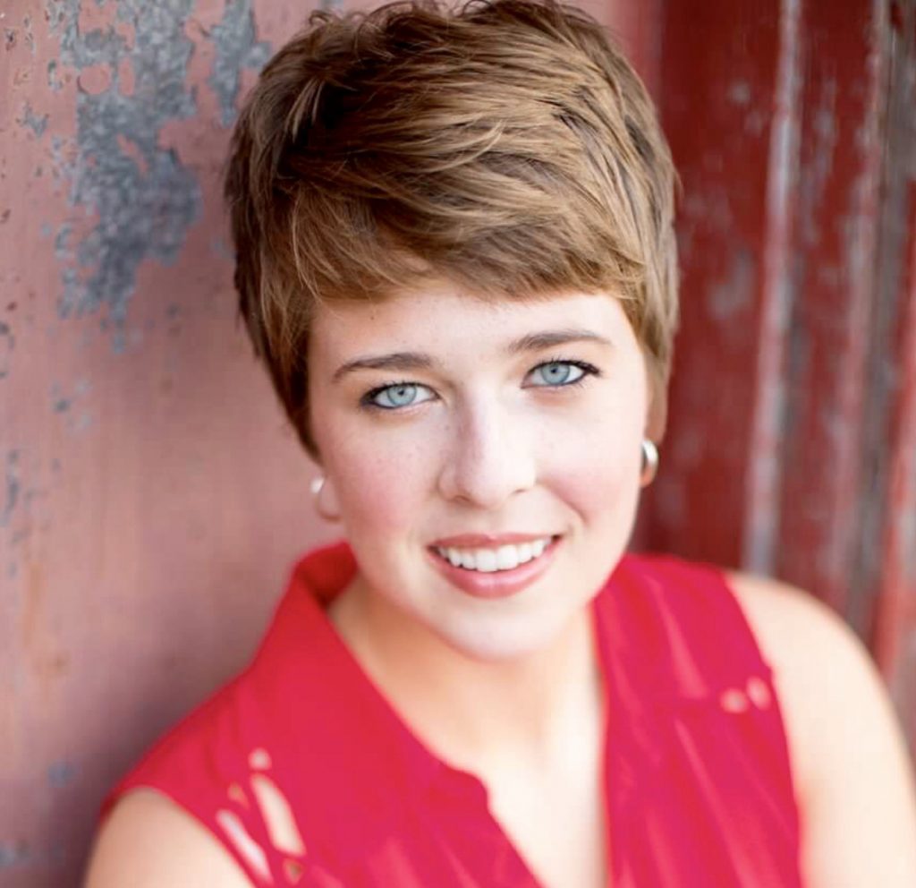 Headshot of Sarah Homoky wearing a red sleeveless blouse