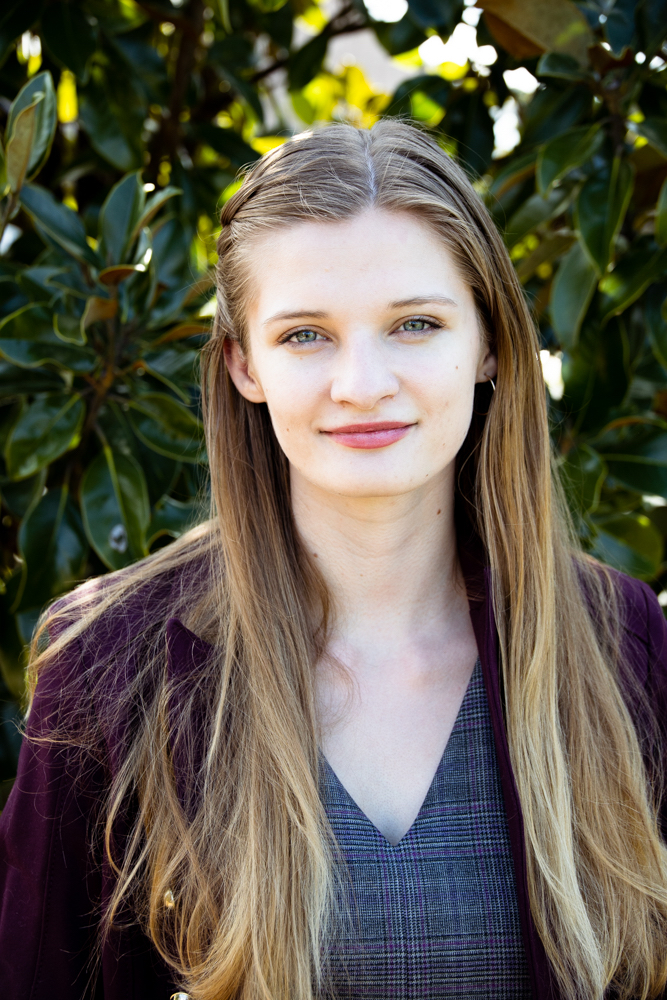 Headshot of Tegan Murrell wearing a brown blazer