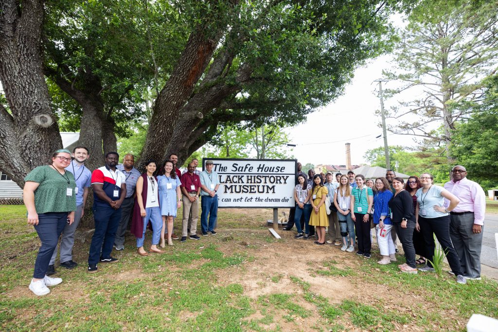 People standing aside The Safe House Black History Museum sign