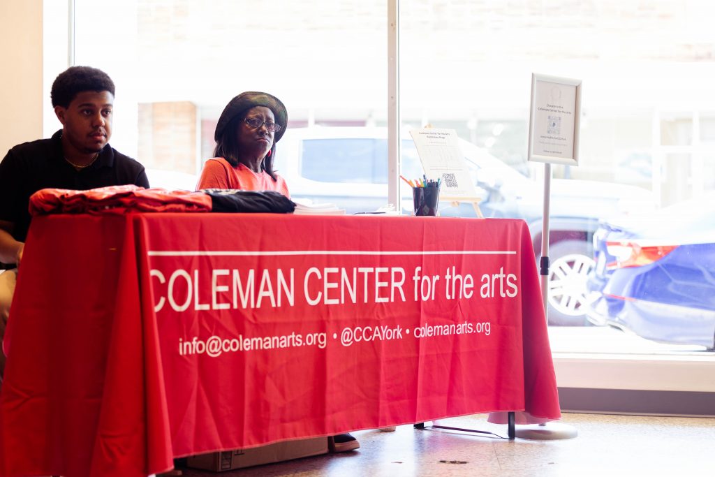 Older lay and younger boy sitting at a red clothed table for Coleman Center for the Arts