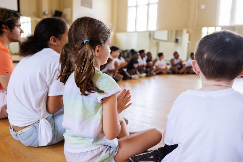 Young kids sitting on the floor of a gym