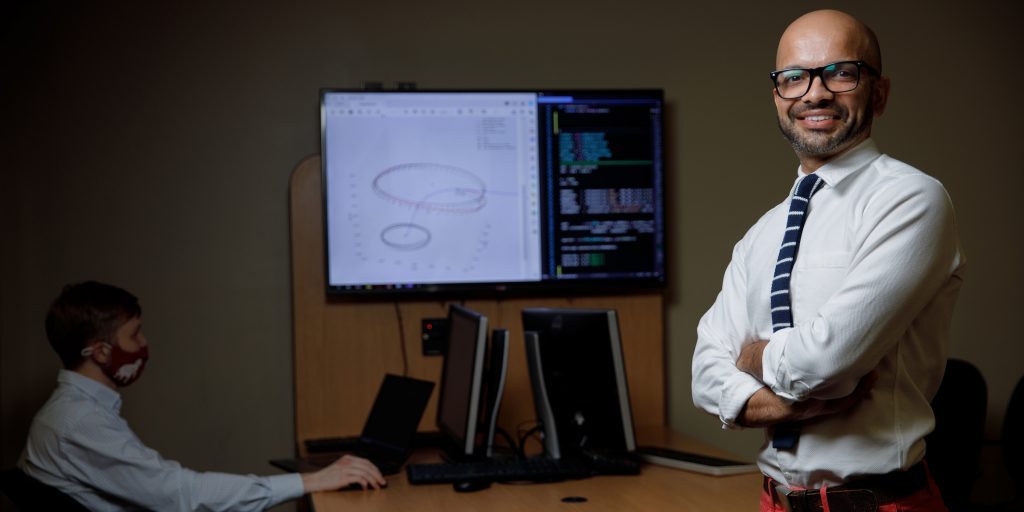 Man standing next to a monitor displaying an aerospace diagram