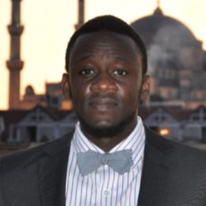 Headshot of Adedeji Akindele-Alo wearing a dark suit and blue bow tie