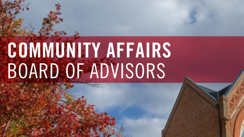 Image of blue clouded sky, tree with fall colored leaves, and the corner roof of a building with a red banner reading Community Affairs Board of Advisors