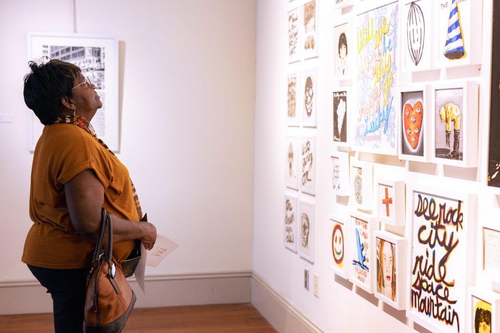 A woman looking at a wall of student made art