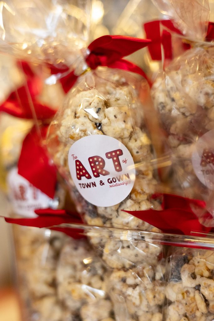 A bag of popcorn with a red bow and art logo