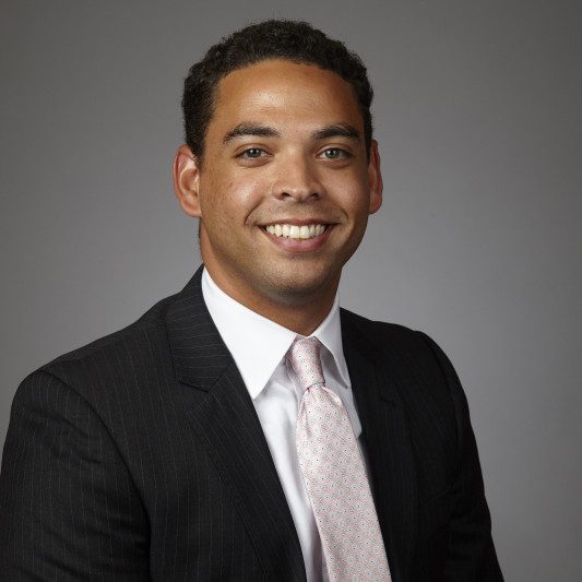 Headshot of Beau DeVaul wearing a black suit and pink tie