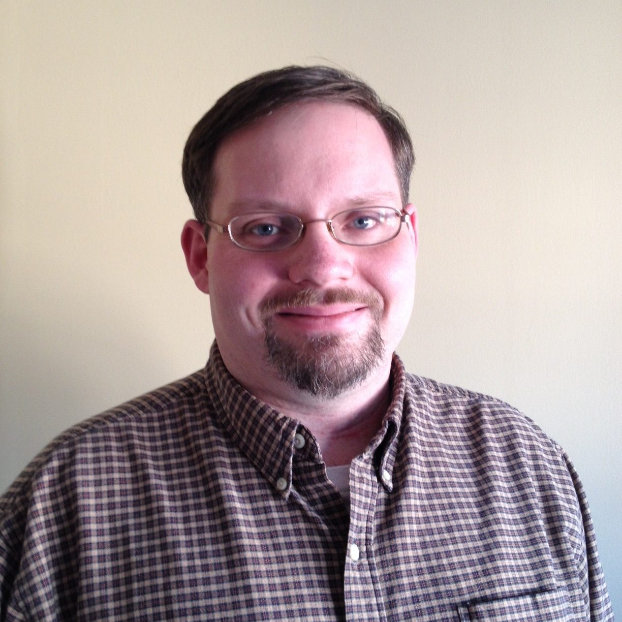 Headshot of Chris Sanders wearing a brown plaid shirt