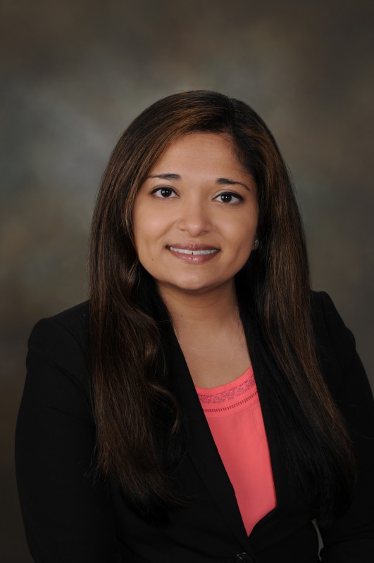 Headshot of Divya Patel wearing a black blazer and pink blouse