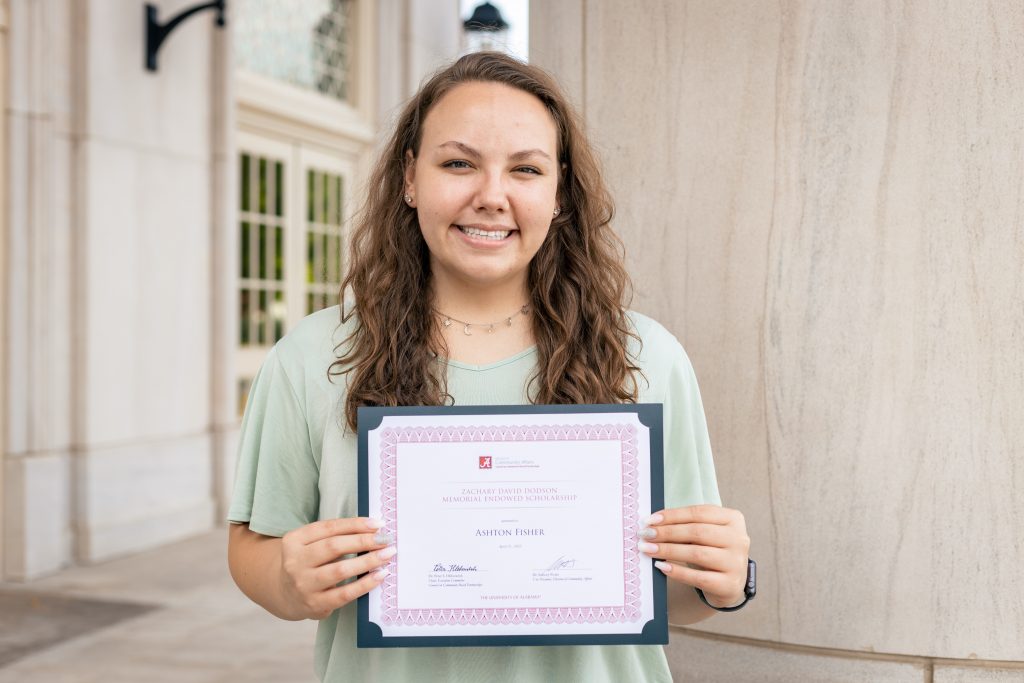 Ashton Fisher smiling and holding a certificate