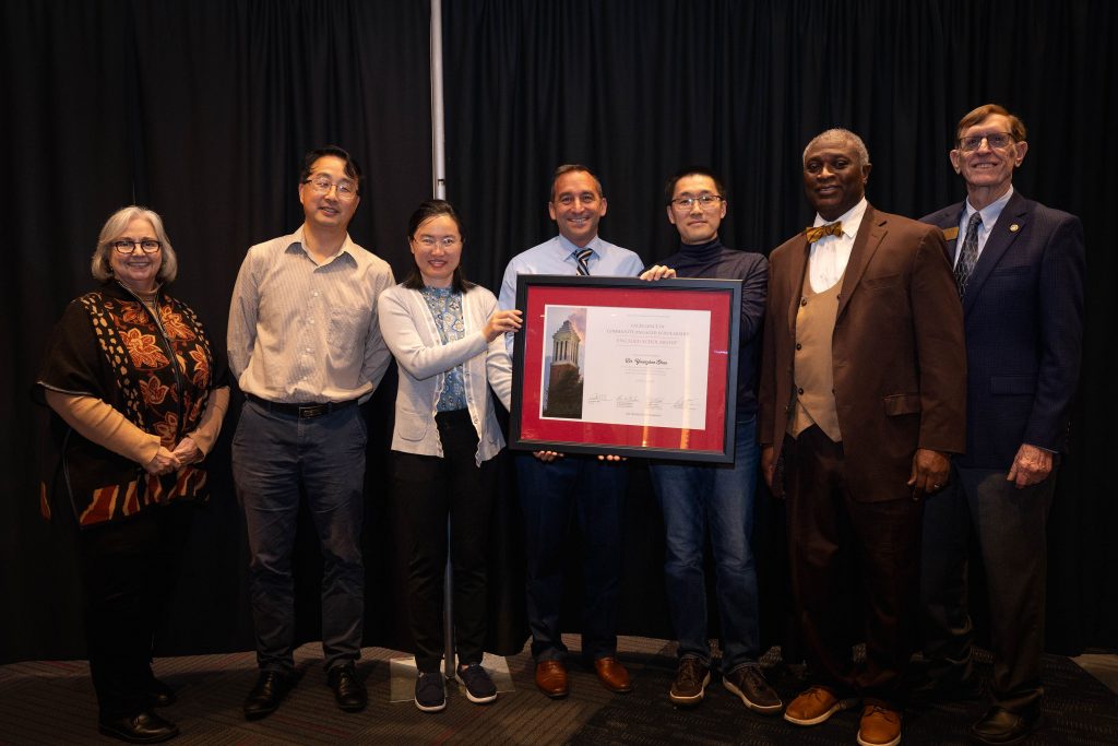 A group of award winners standing together and holding a framed award