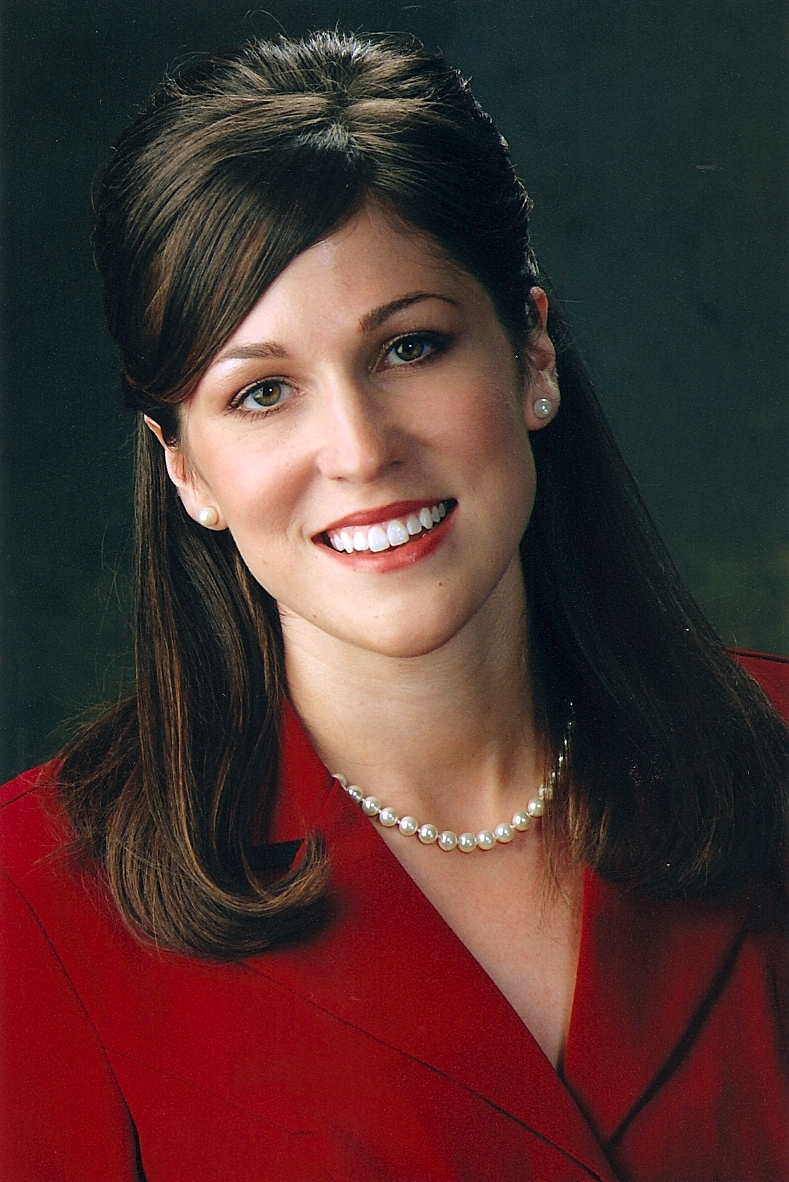 Headshot of Holly Luther wearing a red blazer and pearl necklace