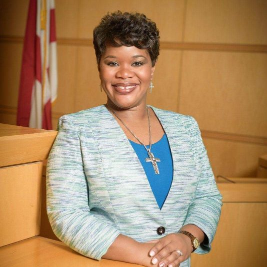 Headshot of Kechia Davis wearing a gray blazer and blue dress