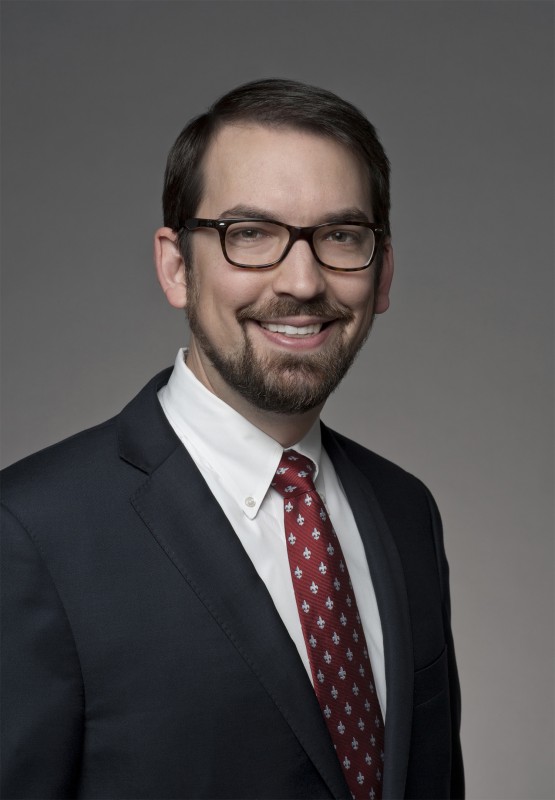 Headshot of Kevin Garrison wearing a dark suit and red patterned tie