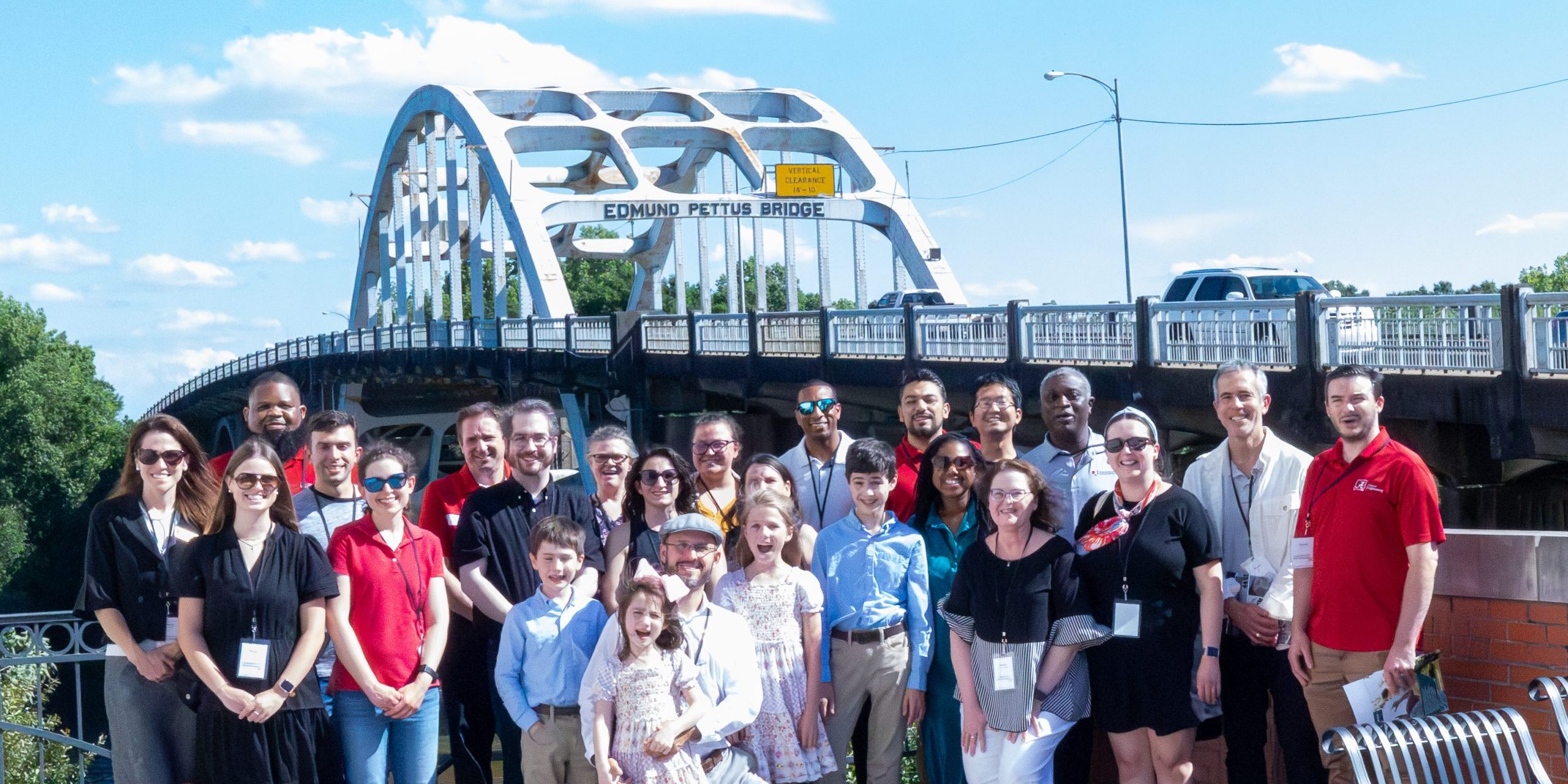 Group of people on the 2024 New Faculty Community Engagement Tour posing in front of a bridge