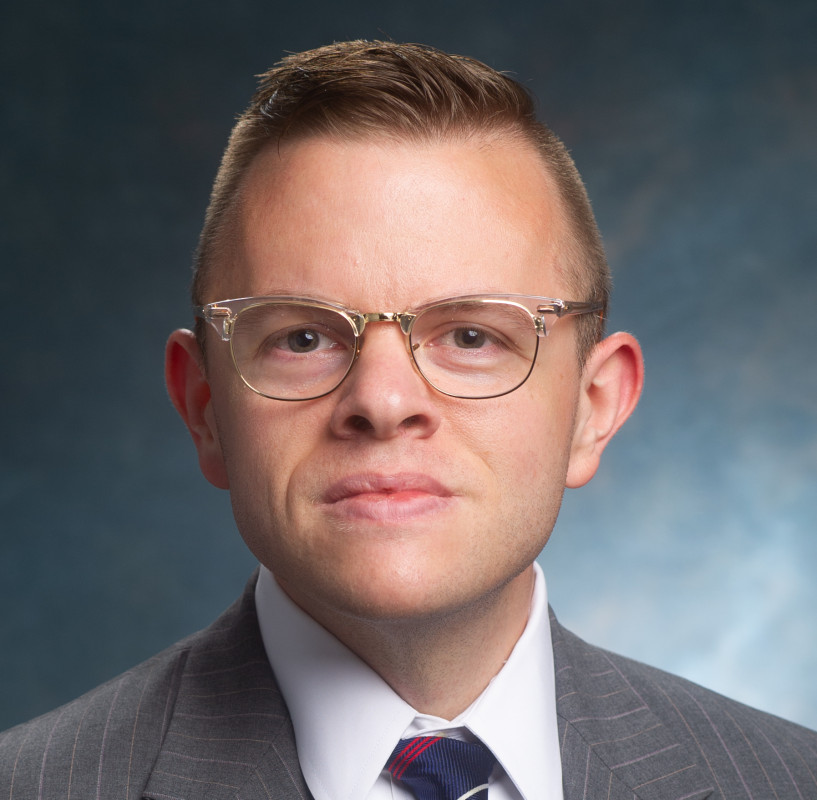 Headshot of Will Nevin wearing a gray suit