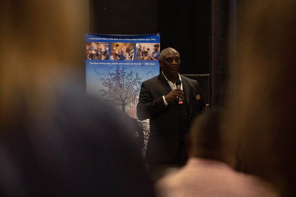 An African American man in a suit speaking into a microphone