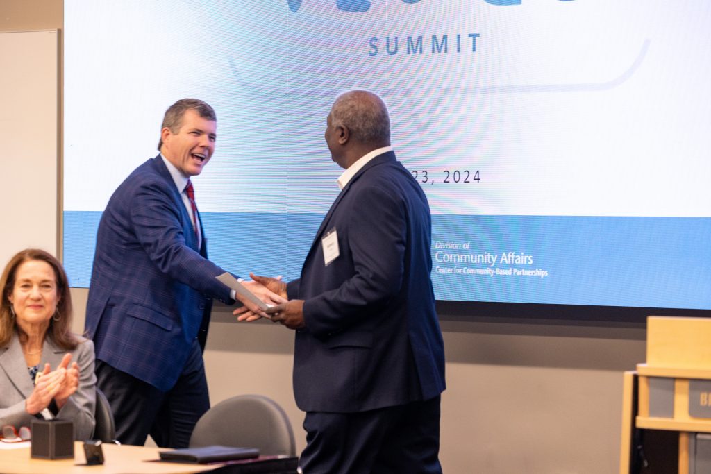 People shaking hands in front of a presentation monitor