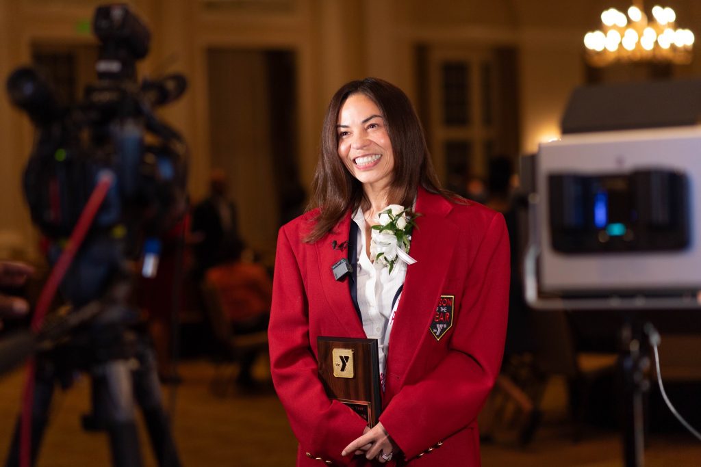 Samarria Dunson wearing a red jacket, smiling and holding an award