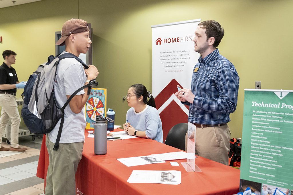 Two people talking at a booth explaining HomeFirst