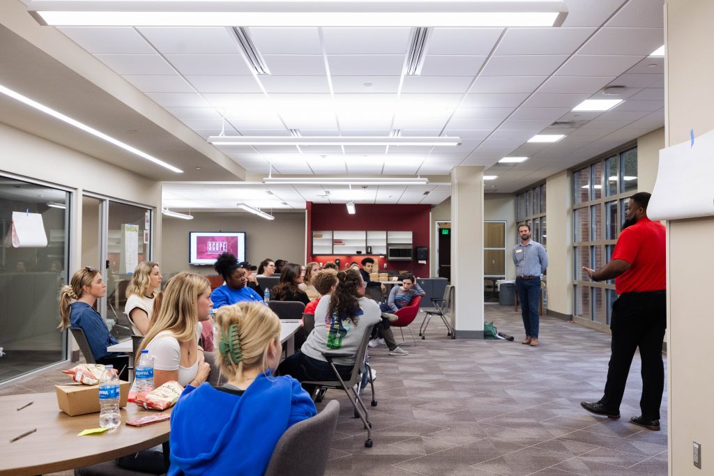 Students gathered at tables in UA’s Student Community Engagement Center for a SCOPE meeting.
